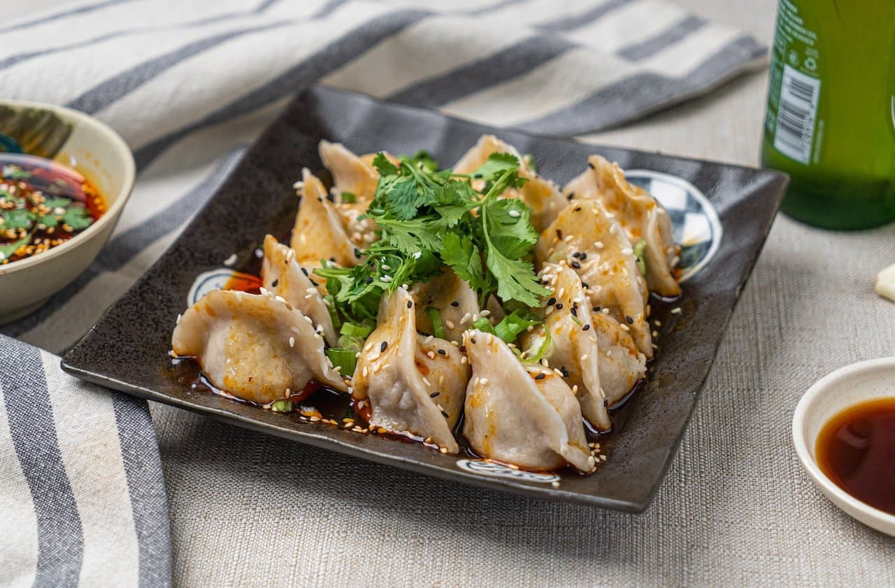 Szechuan Spicy Pork & Napa Cabbage Dumpling - Dumplings served in a fiery Szechuan hot chili sauces. A tantalizing dish with a | Appetizer